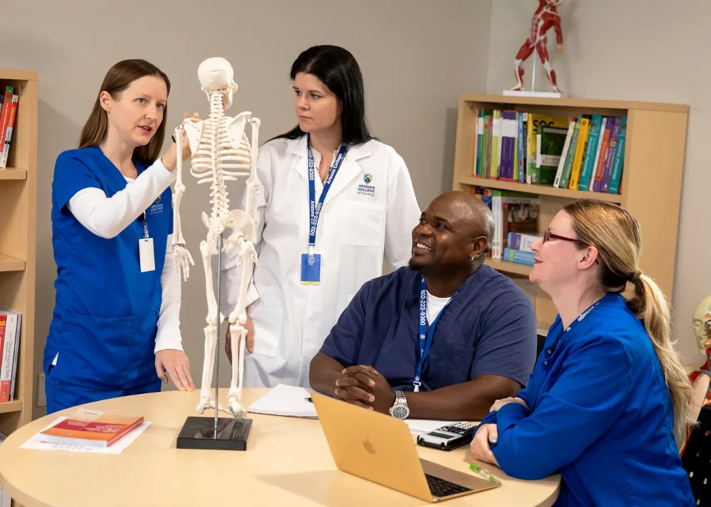 Virginia Nursing program students and faculty standing next to a book shelf at Arizona College