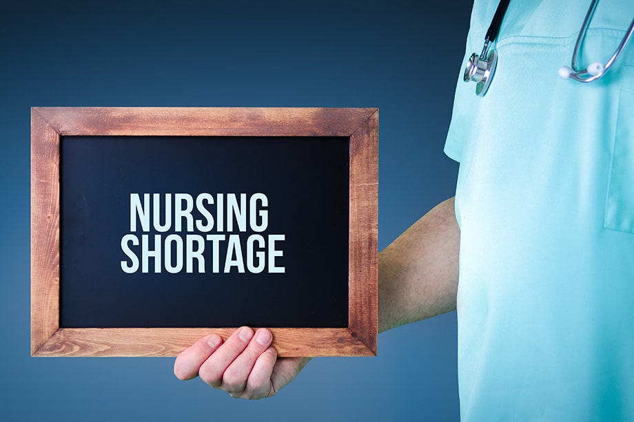 Registered nurse holding nursing career shortage sign