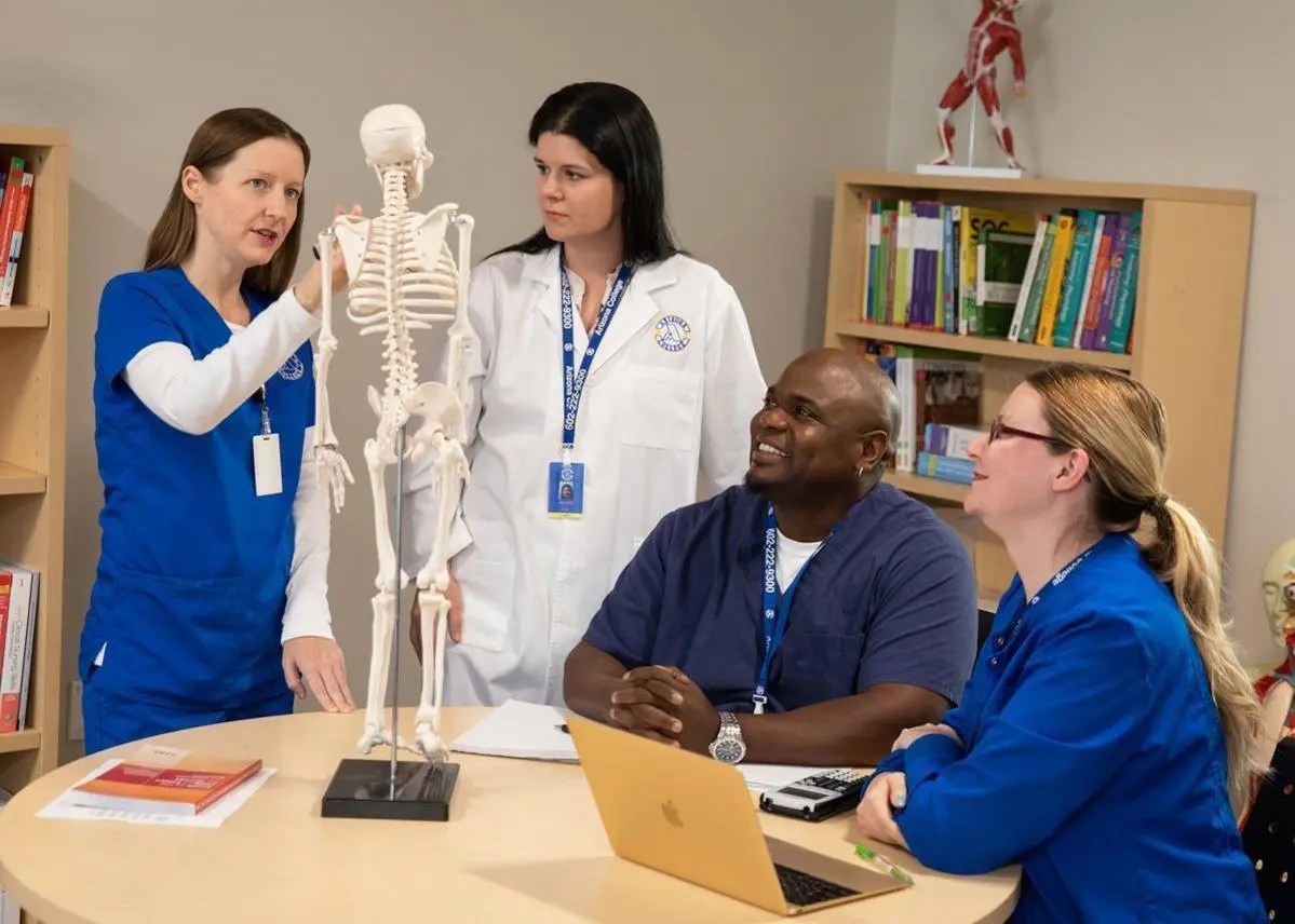 Dallas nursing program students and faculty standing next to a book shelf at Arizona College